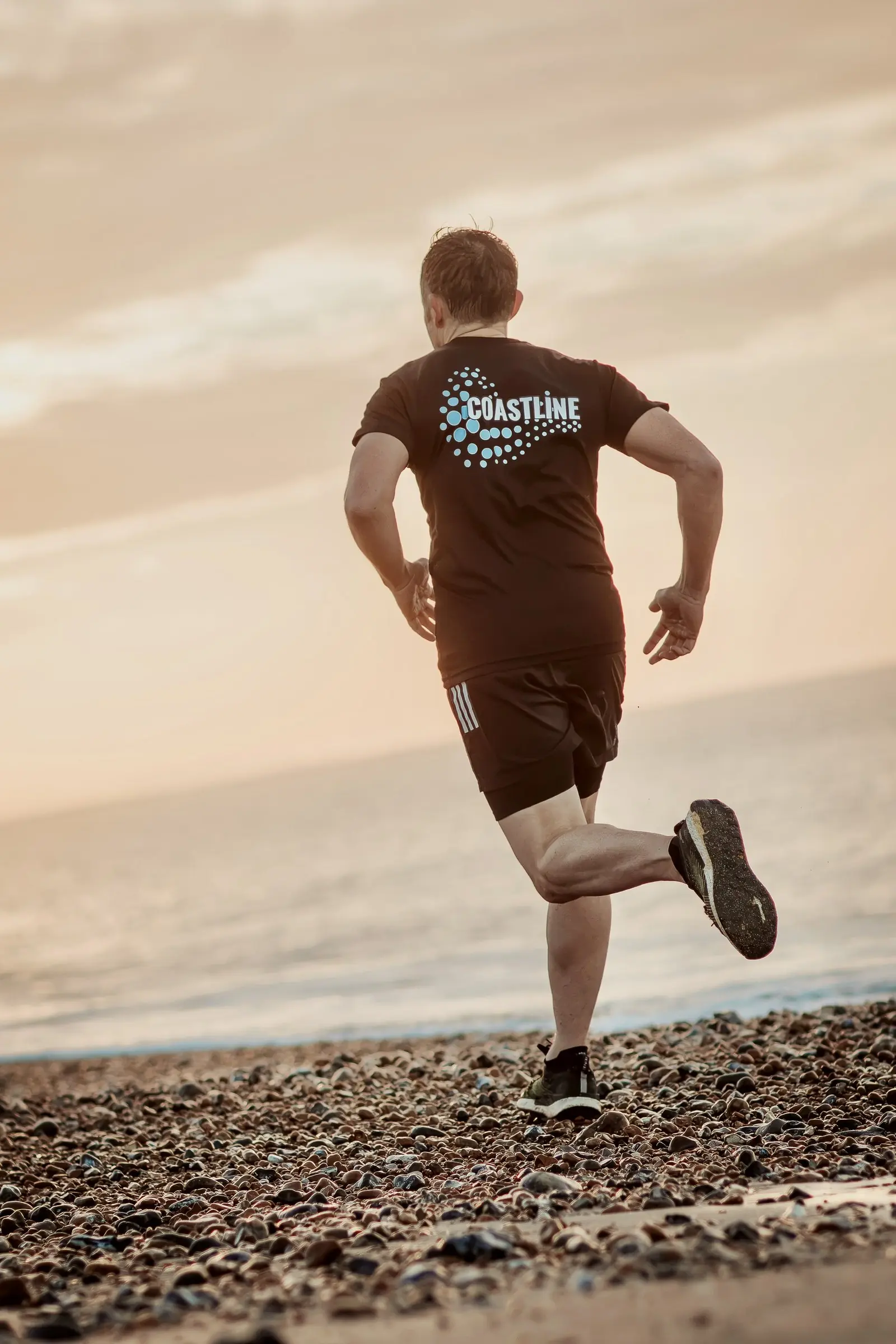 Mark running away along the beach, the Coastline wave logo on the back of his T-shirt