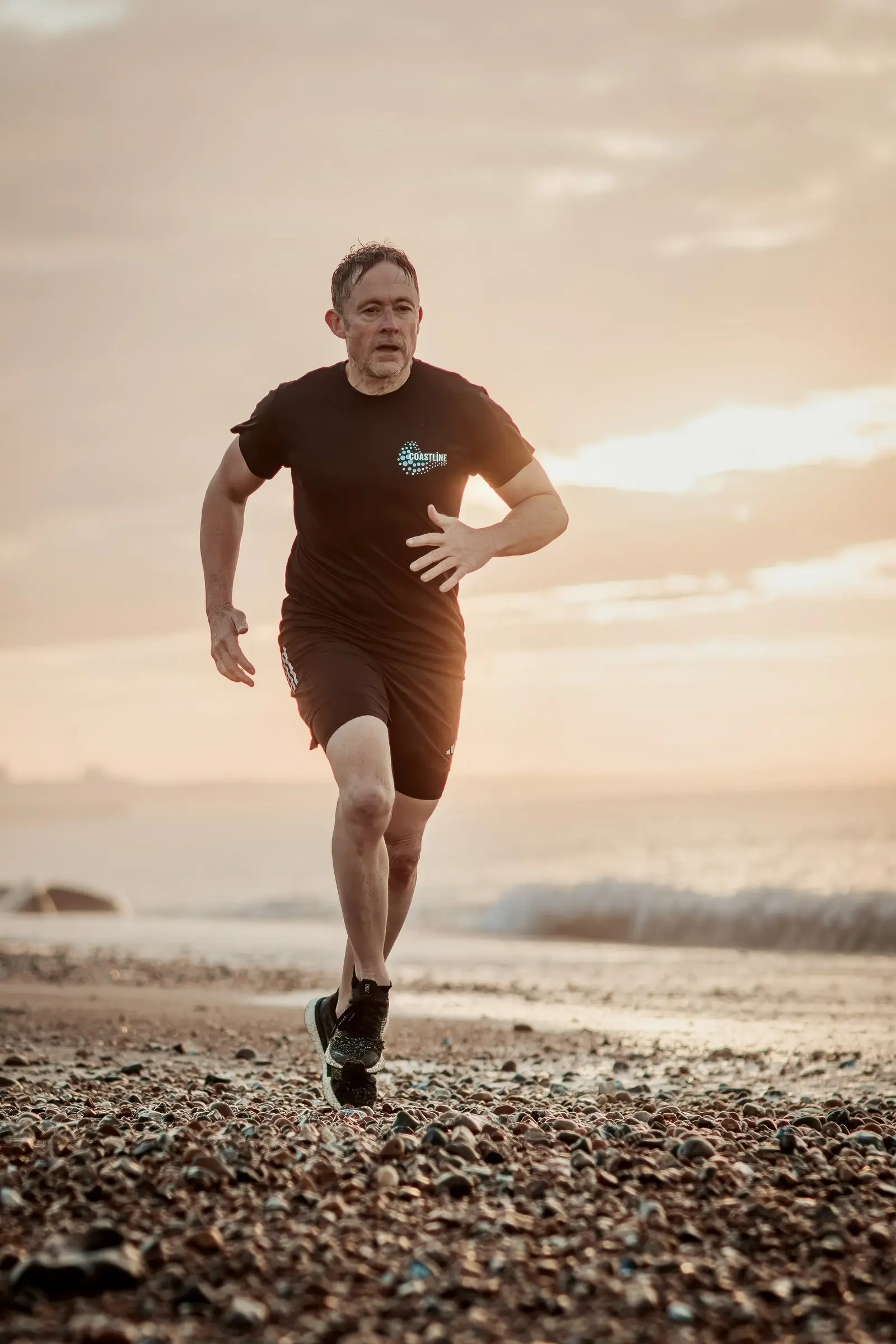 Mark running towards the camera along the shingle in warm morning light
