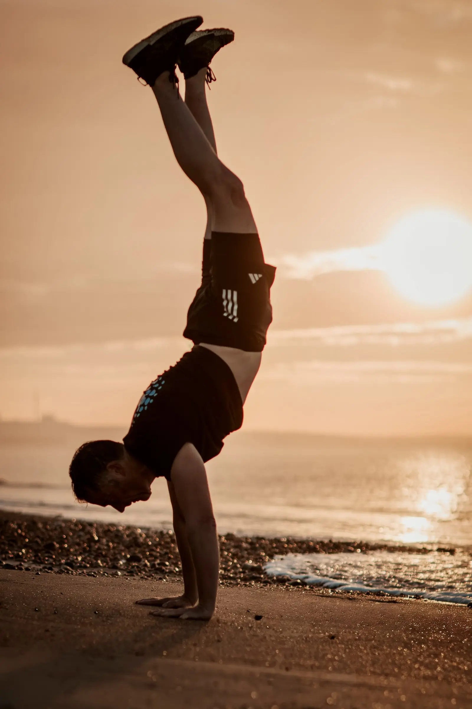 Mark in a handstand on the beach with the low sun behind him