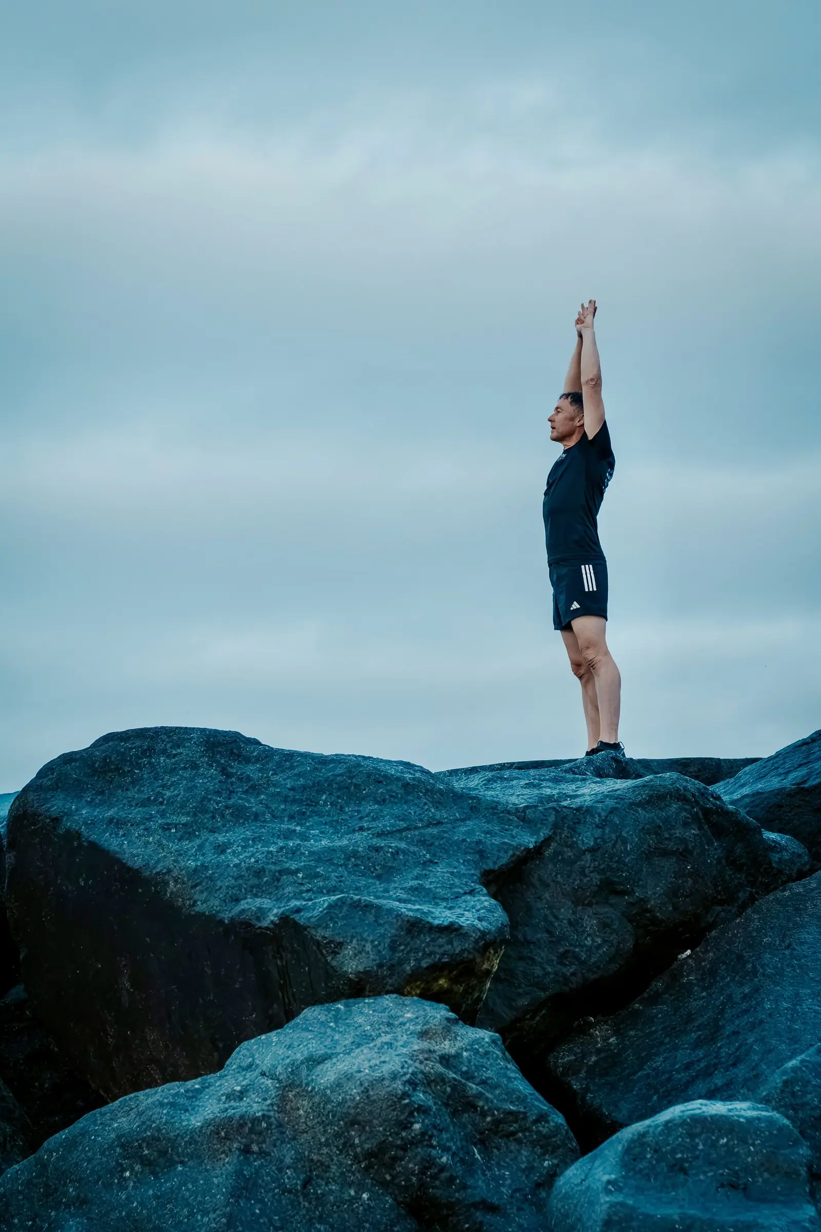 Mark standing on the tallest rock with one arm stretched to the sky