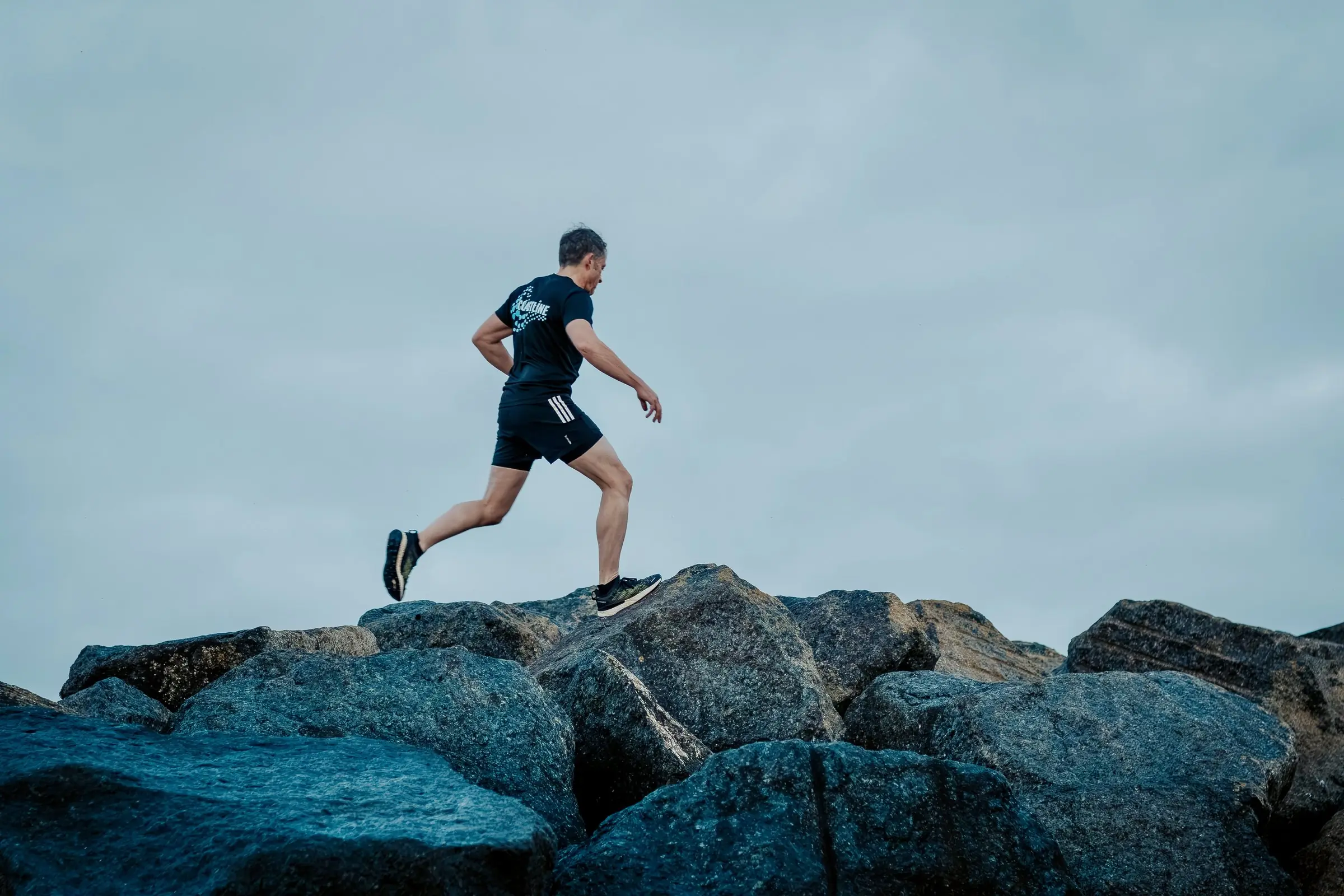 Mark running across the top of the rock groyne, the sea behind him