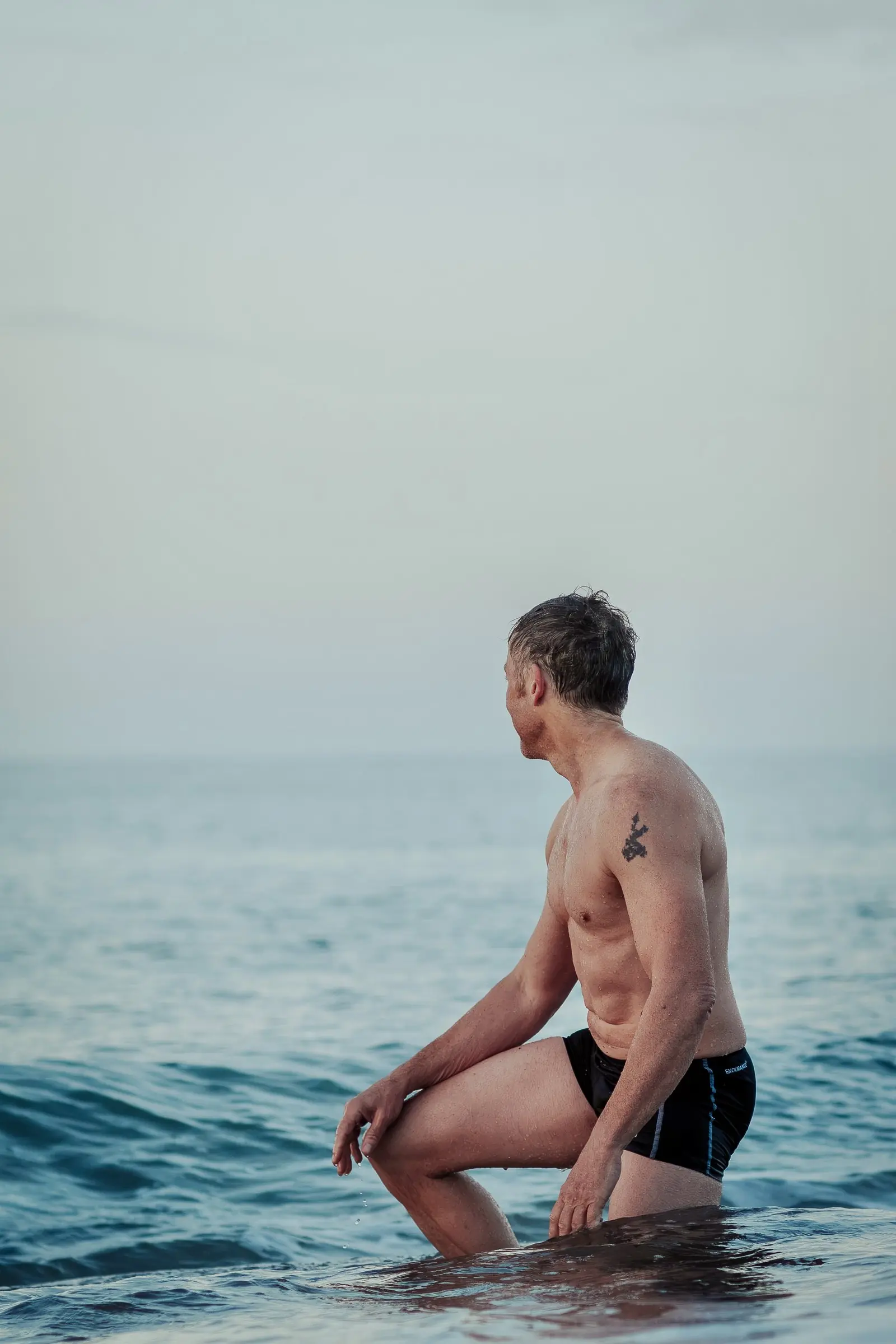 Mark kneeling in the sea, looking along the coast